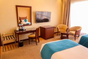 a hotel room with a bed and a desk and a mirror at Palette Luxury Marina View Formerly Happy Days Hotel in Manama