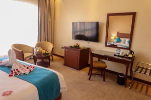 een hotelkamer met een bed, een bureau en een spiegel bij Happy Days Hotel in Manamah