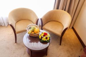 two chairs with a table with a basket of fruit and flowers at Happy Days Hotel in Manama