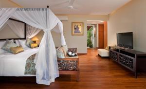 a bedroom with a canopy bed and a television at Villa Joss Seminyak by Nagisa Bali in Seminyak