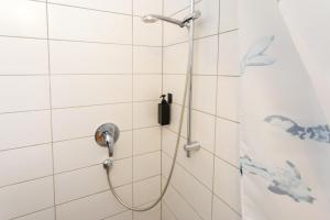 a shower with a hose in a white tiled bathroom at FULL HOUSE Premium Apartments - Halle Paulusviertel in Halle an der Saale