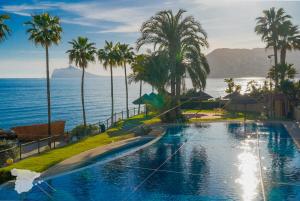 una piscina junto al océano con palmeras en Paradero de Ifach Sotavento CostaBlancaDreams, en Calpe