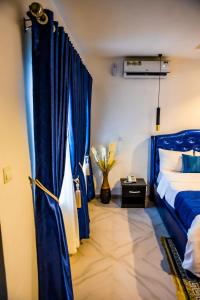 sypialnia z niebieskim łóżkiem i niebieskimi zasłonami w obiekcie El Elyon Hotel and Suites w mieście Lagos