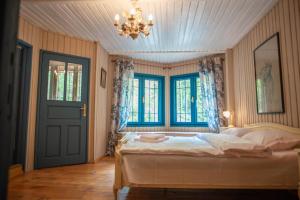 a bedroom with a bed and windows and a chandelier at Villa Sara in Sinaia near Peles & Gondola in Sinaia