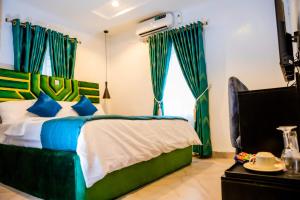 sypialnia z łóżkiem z niebieskimi i zielonymi zasłonami w obiekcie El Elyon Hotel and Suites w mieście Lagos