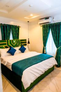 sypialnia z dużym łóżkiem z niebieskimi i zielonymi zasłonami w obiekcie El Elyon Hotel and Suites w mieście Lagos
