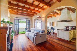 a living room with a couch and a kitchen at Casa con Piscina climatizada, Jacuzzi, Billar, Aire Acondicionado in Sant Lluis