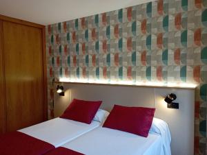 2 camas en una habitación de hotel con almohadas rojas en Apartamentos VIDA Sanxenxo, en Sanxenxo