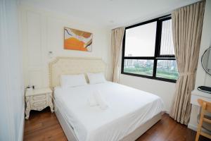 a white bedroom with a bed and a window at D'capitale - Feria Homes in Hanoi