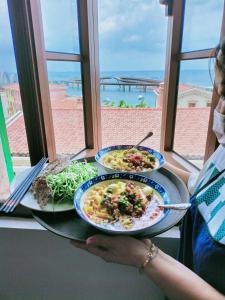 une femme détenant deux assiettes de nourriture sur une table dans l'établissement Sunset Hotel Phu Quoc - welcome to a mixing world of friends, à Duong Dong
