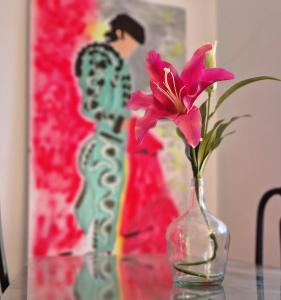 uma flor rosa num vaso de vidro sobre uma mesa em Calzada 10 em Sevilha