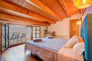 1 Schlafzimmer mit einem Bett und einem Balkon mit Stühlen in der Unterkunft Casa con Piscina climatizada, Jacuzzi, Billar, Aire Acondicionado in Sant Lluís
