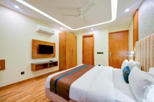 a bedroom with a large bed and a tv at FabHotel Soft Petals in Gurgaon
