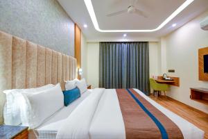 ein Hotelzimmer mit einem großen Bett und einem Schreibtisch in der Unterkunft FabHotel Soft Petals in Gurgaon