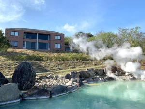 a building with smoke in front of a pool of water at Manden in Beppu