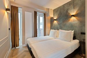 una camera da letto con un grande letto con lenzuola bianche di Midtown Hotel Triple Room ad Amsterdam
