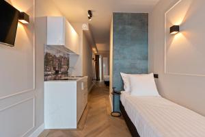 Dormitorio pequeño con cama y lavamanos en Midtown Hotel Triple Room, en Ámsterdam