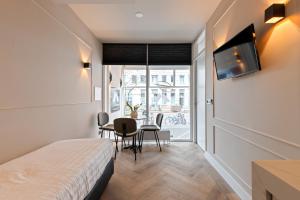 アムステルダムにあるMidtown Hotel Triple Roomのベッド、テーブル、椅子が備わる客室です。