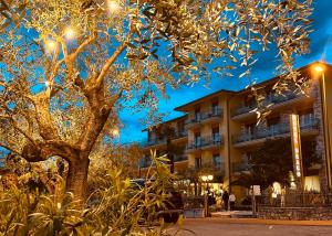 un arbre devant un bâtiment lumineux dans l'établissement Hotel Drago - Garda Lake Collection, à Brenzone