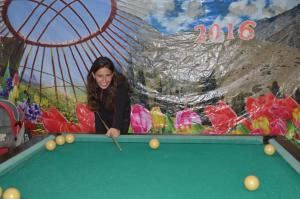 a woman playing pool in front of a mural at Guest House on Derbisheva in Karakol