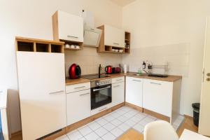 - une petite cuisine avec des armoires et des appareils blancs dans l'établissement FullHouse - Halle - Paulus Apartment - Nespresso, à Halle-sur-Saale 15 autres photos