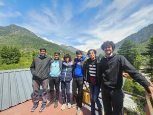 a group of people posing for a picture on a balcony at Hotel Old Manali - The Best Riverside Boutique Stay with Balcony and Mountain Views in Manāli