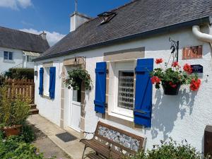 una casa azul y blanca con persianas azules y un banco en Gîte Ty Bihan Baradoz, en Scrignac
