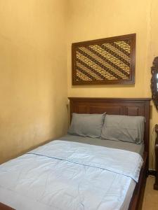 a bed with a wooden headboard in a room at Good Feeling Hostel in Banyuwangi