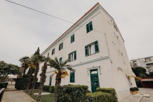 a white building with a green door and palm trees at Rooms and Studios Villa Rossella 2 in Rovinj