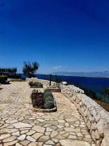 a stone walkway with a stone wall next to the water at Apartmani Franka in Privlaka