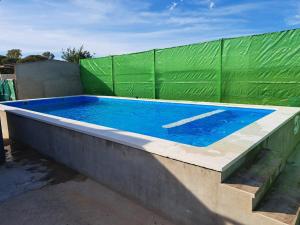 uma piscina com uma cerca verde à volta em Finca El Abuelo em Lepe