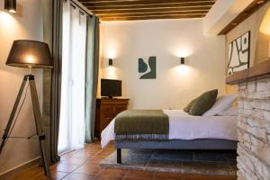 a bedroom with a bed and a lamp and a television at In Provence Hôtel - Hôtel de Charme in Venelles