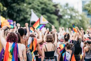 una multitud de personas sosteniendo banderas arco iris en Auberge Alternative, en Montreal