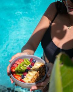 a woman holding a bowl of fruit in front of a pool at Kassandra Boutique Hotel in Oludeniz