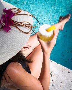 a woman in a hat holding a drink next to a pool at Kassandra Boutique Hotel in Oludeniz