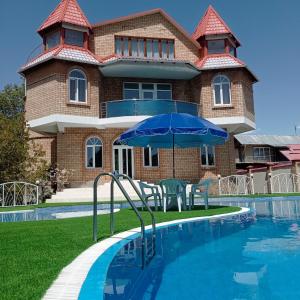 a house with a pool and a blue umbrella at Private Luxury Villa - Issyk Kul in Cholpon-Ata