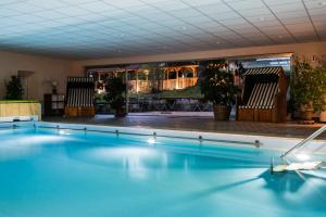 a swimming pool in a room with chairs and plants at Hotel Alpensonne in Bad Wiessee