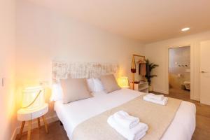 a bedroom with a large white bed with towels on it at Bravissimo Turbau Entresol A, with 3 bedrooms in Girona