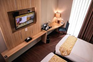 Habitación de hotel con TV, cama y escritorio. en Anara Sky Kualanamu Hotel en Medan