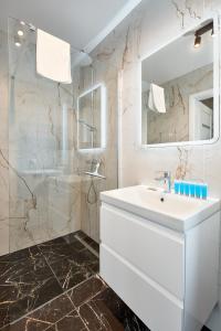La salle de bains blanche est pourvue d'un lavabo et d'une douche. dans l'établissement Poznań Airport Homely Apartment, à Poznań