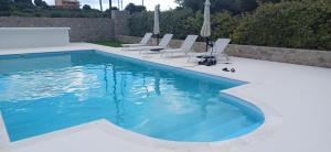 - une piscine avec des chaises blanches dans l'établissement Villa Maria, à Porto Heli