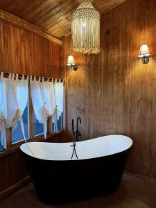 eine Badewanne im Bad mit Kronleuchter in der Unterkunft Retro House Mộc Châu in Mộc Châu