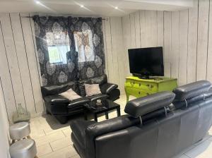 a living room with leather chairs and a television at gîte coeur de champagne in Romery