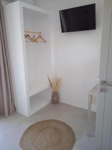 a white room with a television and a rug at Ραχάτι in Áyios Stéfanos