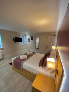 ein Schlafzimmer mit einem großen Bett und einer Lampe in der Unterkunft Holtwhites Hotel in Enfield