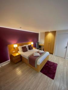 1 dormitorio con cama grande y pared morada en Holtwhites Hotel en Enfield