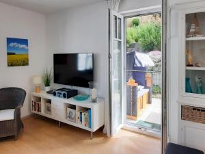 ein Wohnzimmer mit einem TV und einer Glasschiebetür in der Unterkunft Villa Rosa - Apt. 15 in Ostseebad Sellin
