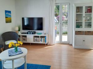 ein Wohnzimmer mit Fernseher und einem Tisch mit Blumen in der Unterkunft Villa Rosa - Apt. 15 in Ostseebad Sellin