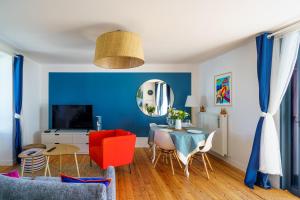 a blue living room with a table and a red chair at Ty Marok - Maison pour 4 proche plage in Douarnenez
