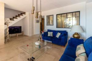 a living room with a blue couch and a glass table at Casa Alegría Casa premium piscina comunitaria in S'agaro
